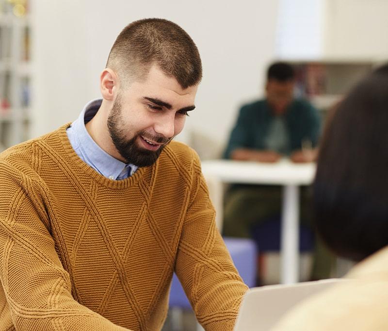 A guy smiling at his laptop